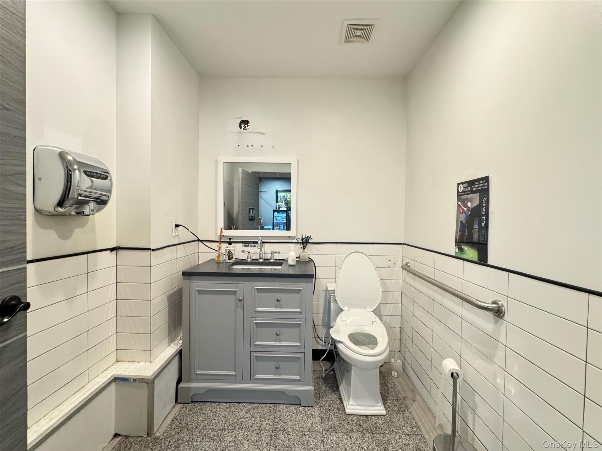 42-16 162nd Street Queens, NY 11358 - Photo 15 of 16 Half bathroom featuring tile walls, a wainscoted wall, and vanity