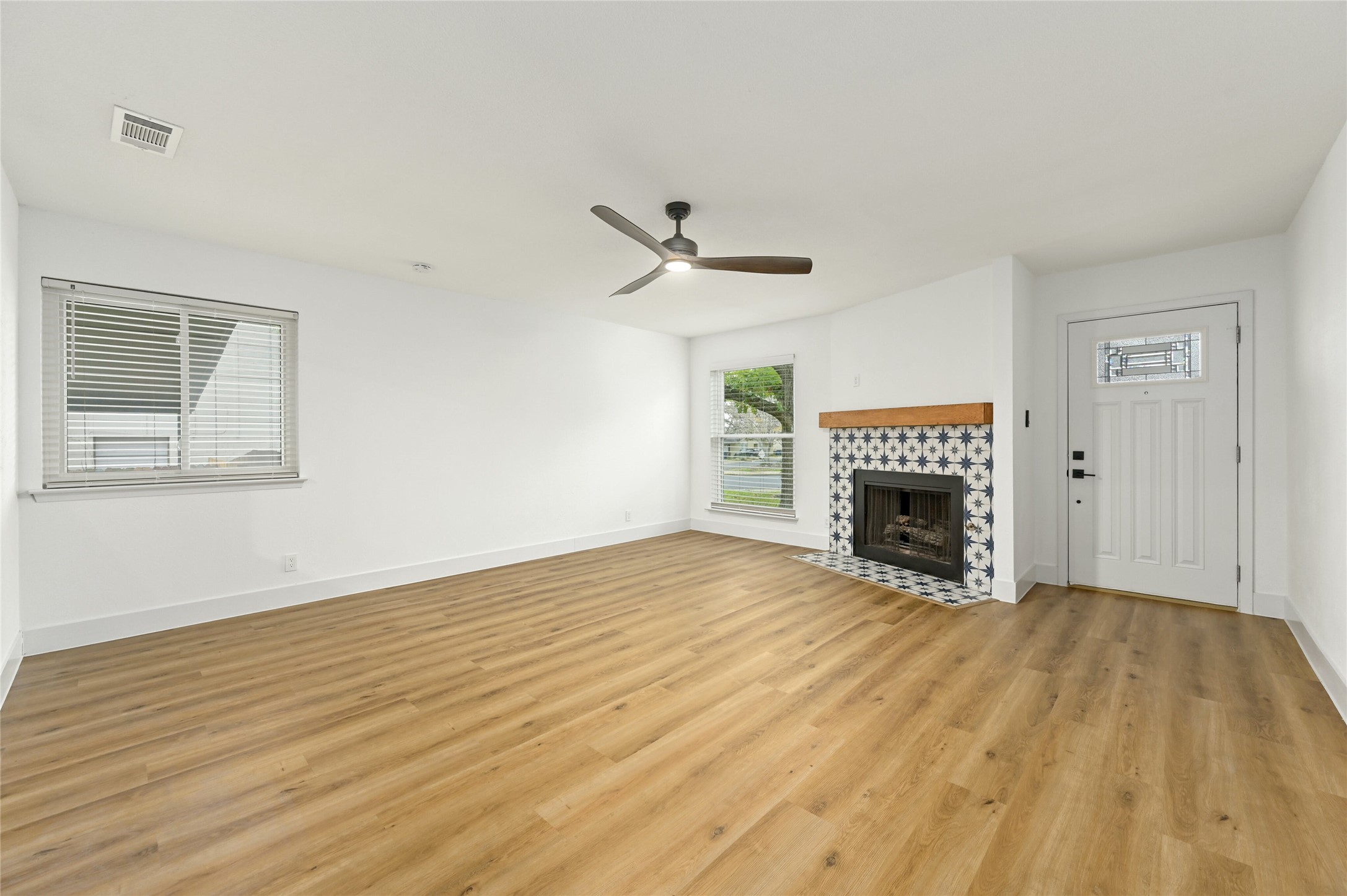 4808 Wind River Road Austin, TX 78759 - Photo 3 of 21 Warm wood flooring and a tiled fireplace elevate this inviting entry space.