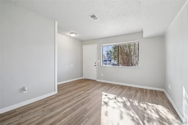 an empty room with wooden floor cabinet and windows