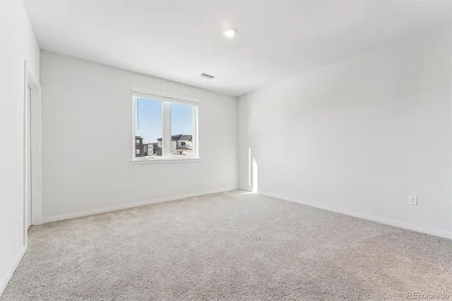an empty room with windows and refrigerator