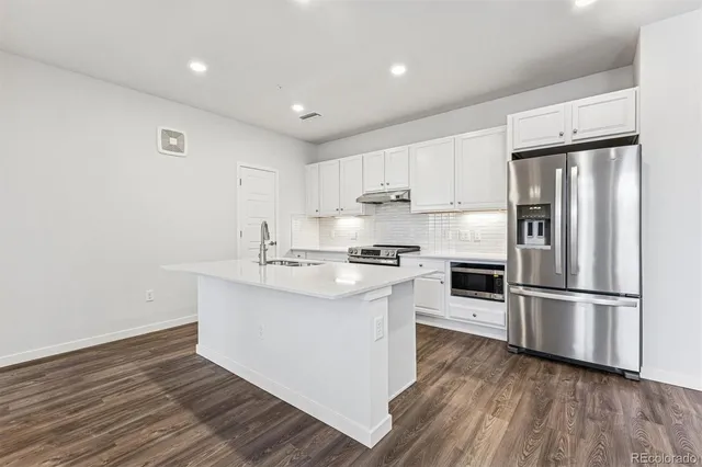 a kitchen with wooden floors white cabinets and stainless steel appliances
