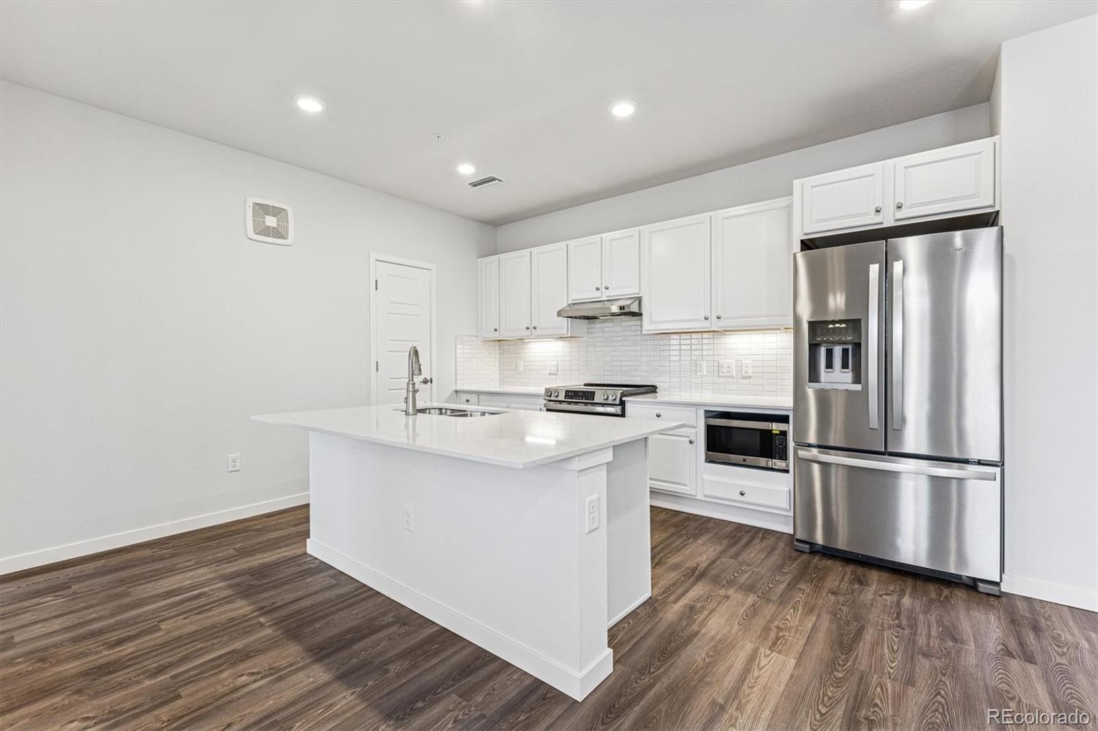 485 Interlocken Boulevard, Unit 210 Broomfield, CO 80021 - Photo 2 of 15 a kitchen with wooden floors white cabinets and stainless steel appliances