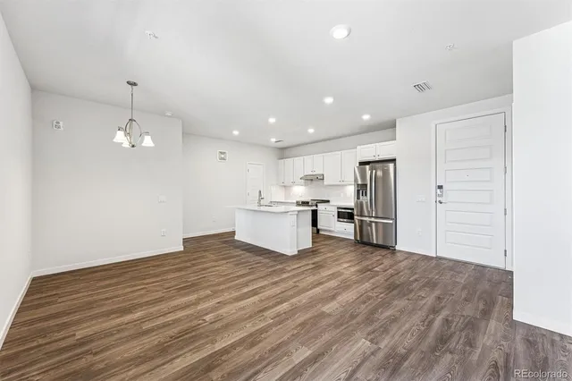 a view of a kitchen with refrigerator and white cabinets