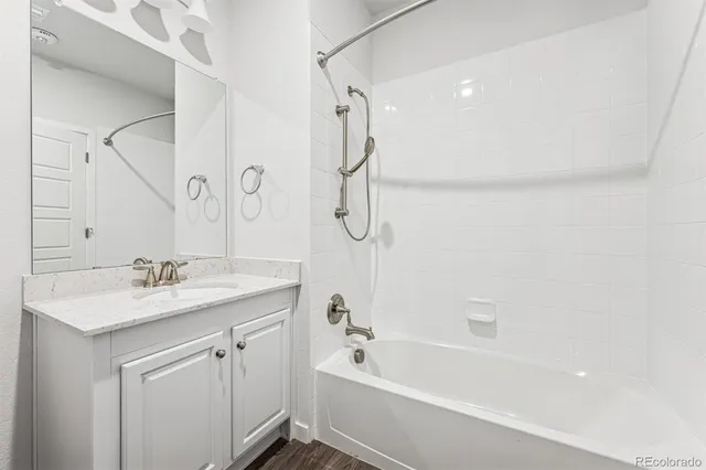 a bathroom with a tub sink vanity granite and shower