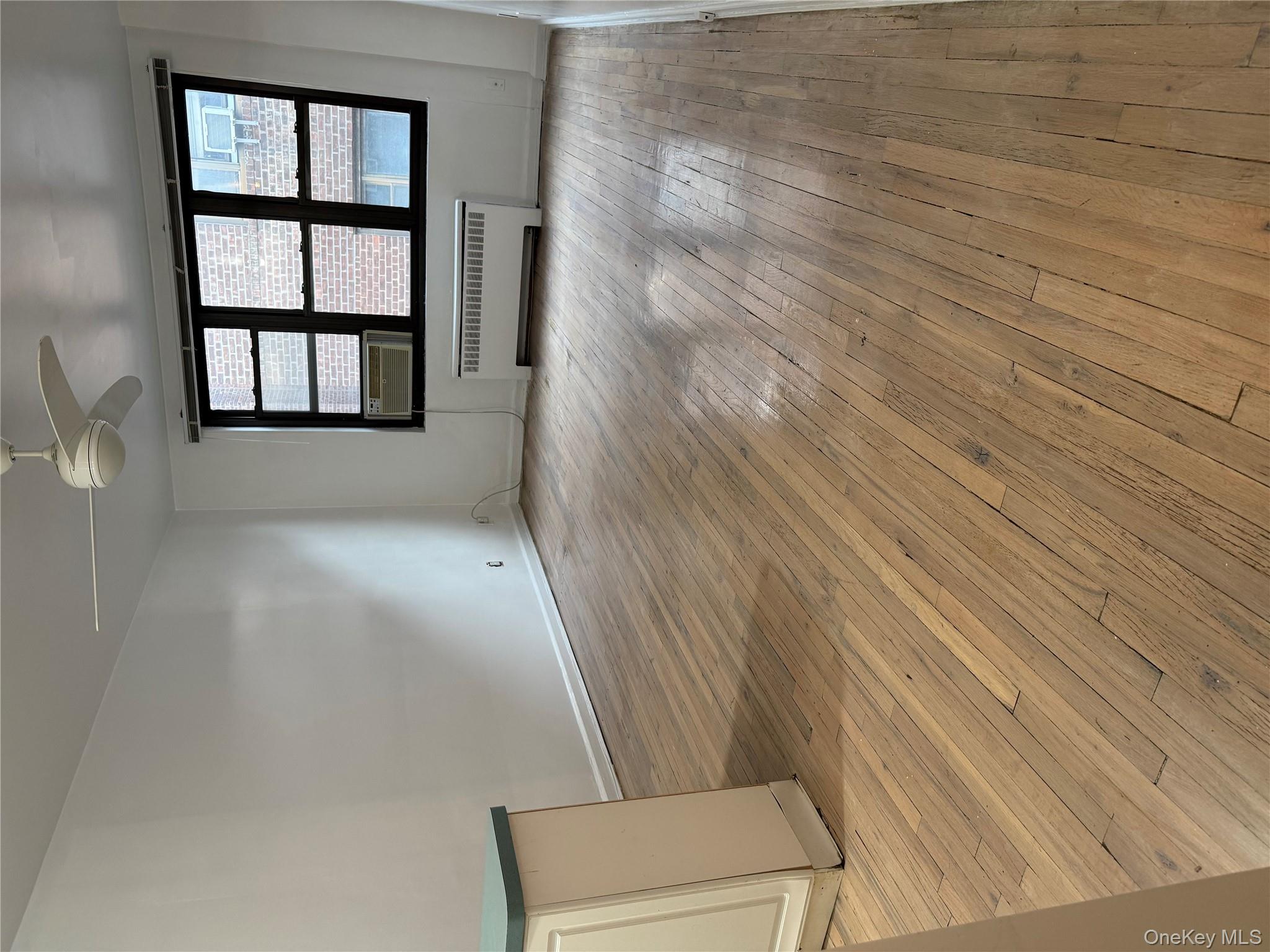 15 Canterbury Road, Unit D13 Great Neck, NY 11021 - Photo 6 of 9 a view of an empty room with a window and wooden floor