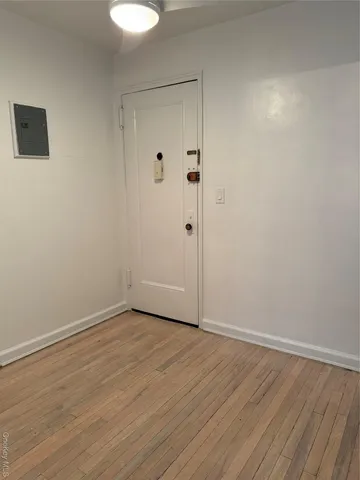 a view of an empty room with a window and wooden floor