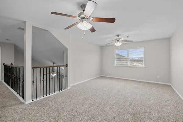 a view of an empty room with a chandelier fan