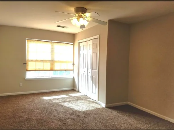 an empty room with a chandelier fan and windows