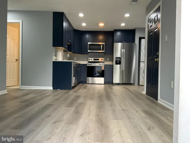 a view of kitchen with stainless steel appliances kitchen island granite countertop a refrigerator and a stove top oven
