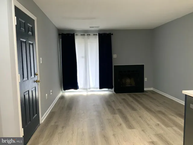 a view of an empty room with a fireplace and a window