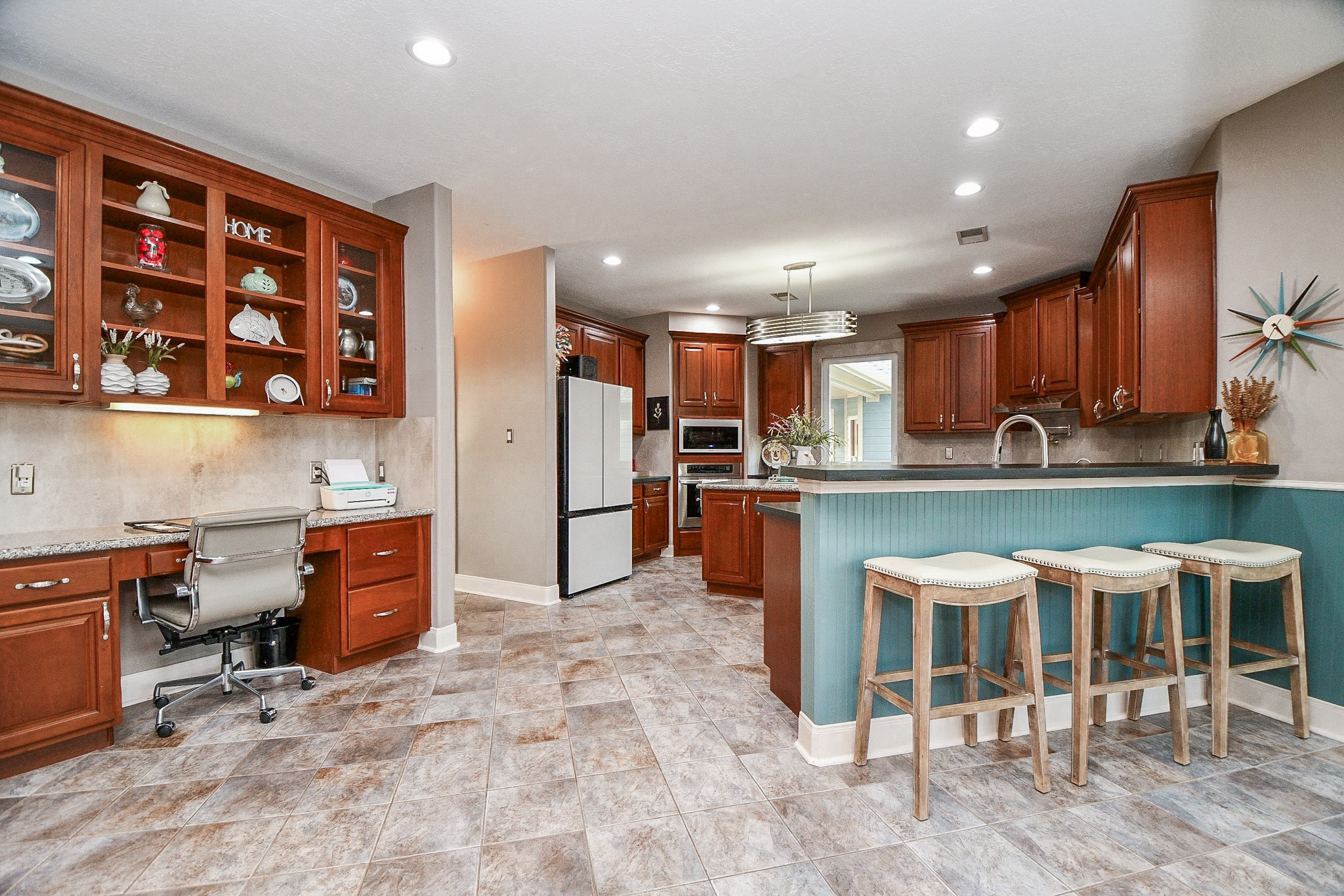 3680 Eula Morgan Road Katy, TX 77493 - Photo 15 of 50 Big or small, kitchens are always the hub of the home! In this case, rich amber toned cabinetry fills walls up and down (with the benefit of desk/counter space, left); beautiful, neutral toned tile flooring, spacious counter area (right) with ample stool room below, and gleaming stainless steel appliances in a deliciously spacious kitchen.