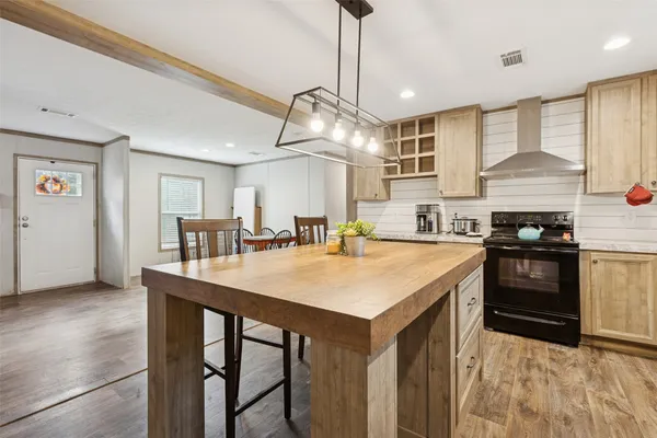 a kitchen with kitchen island a stove a table and chairs in it