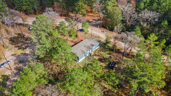 an aerial view of residential house with outdoor space and trees all around