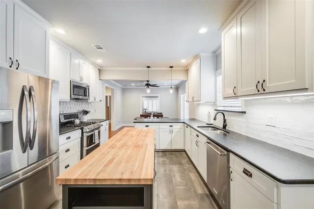 a large kitchen with stainless steel appliances granite countertop a sink a stove and a refrigerator