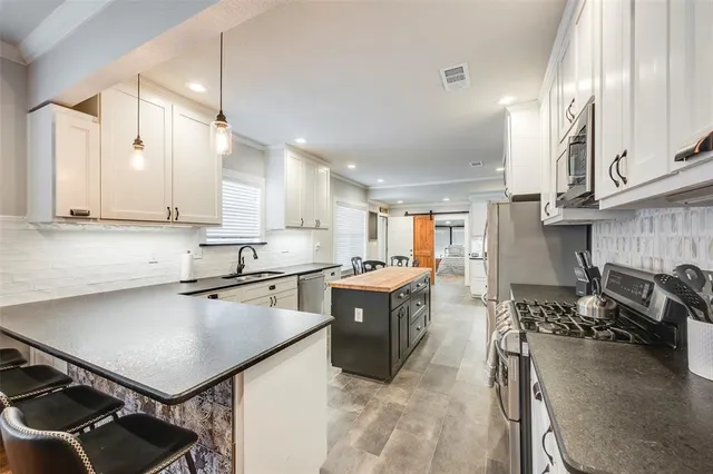 a kitchen with a stove a sink dishwasher and a refrigerator with wooden floor