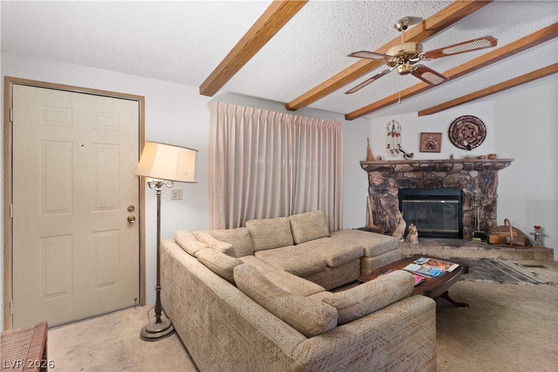 1609 Cajon Court Laughlin, NV 89029 - Photo 5 of 69 Carpeted living room featuring ceiling fan, beamed ceiling, and a stone fireplace