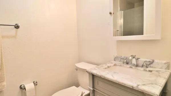 a bathroom with a granite countertop sink a toilet and mirror