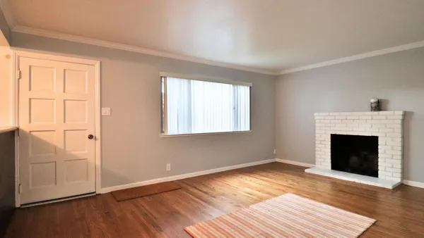 an empty room with wooden floor fireplace and windows
