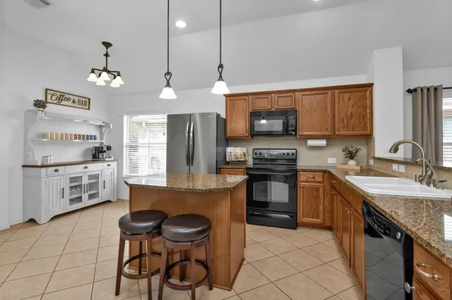 a open kitchen with stainless steel appliances granite countertop a refrigerator a stove top oven a sink dishwasher and white cabinets with wooden floor