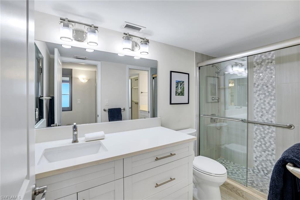 5 Bluebill Avenue, Unit 506 Naples, FL 34108 - Photo 12 of 25 a bathroom with a sink a toilet a mirror and shower