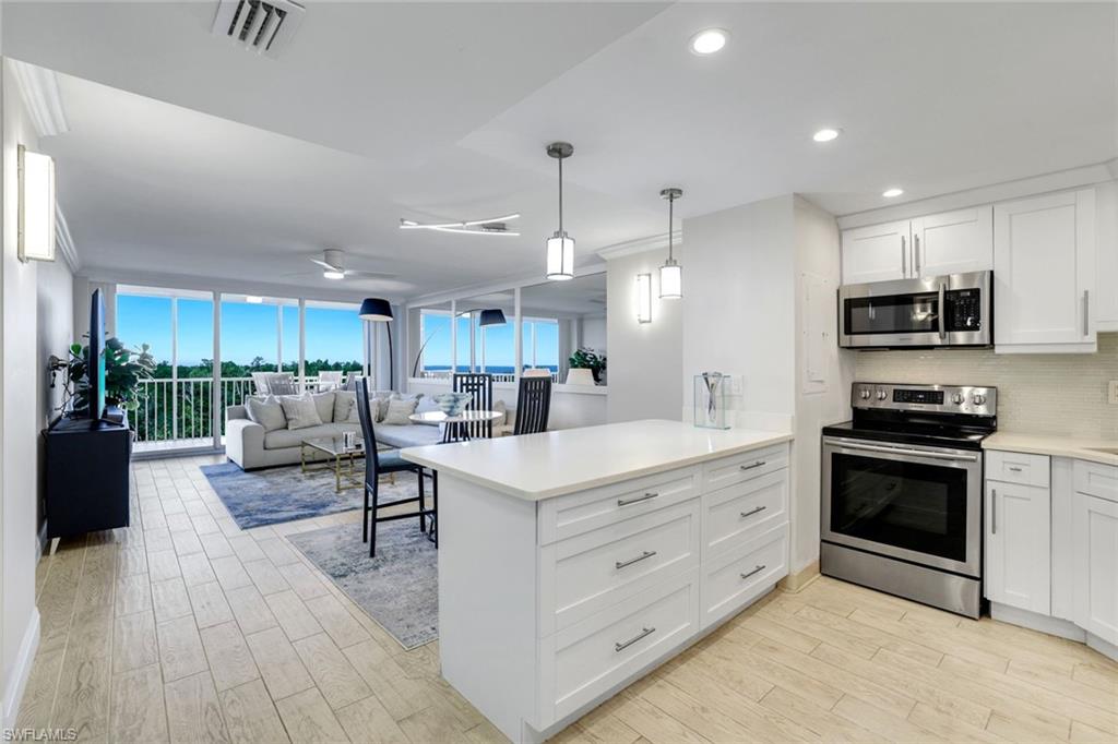 5 Bluebill Avenue, Unit 506 Naples, FL 34108 - Photo 4 of 25 a large white kitchen with stainless steel appliances granite countertop a stove oven and a view of living room