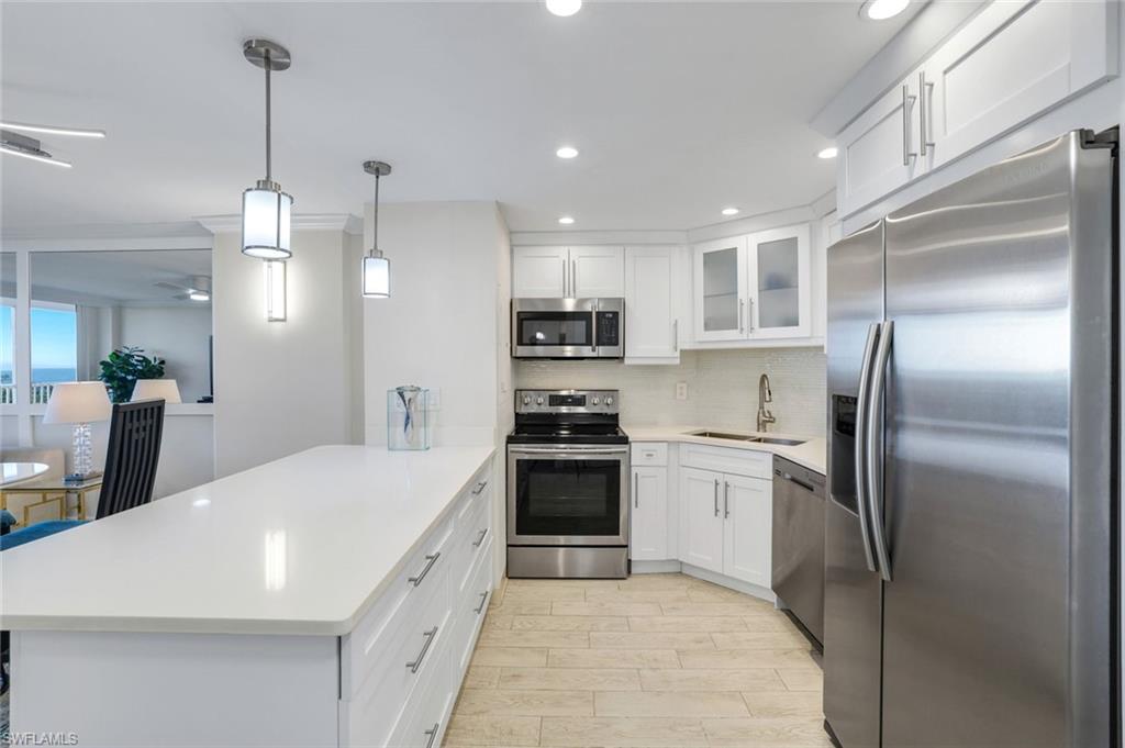 5 Bluebill Avenue, Unit 506 Naples, FL 34108 - Photo 5 of 25 a large kitchen with white cabinets stainless steel appliances and kitchen island
