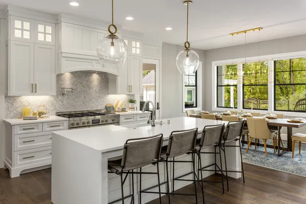 an open kitchen with granite countertop a stove a sink a dining table and chairs with wooden floor