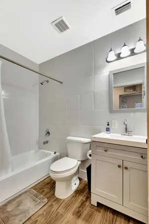 a bathroom with a toilet a sink a mirror a bathtub and vanity