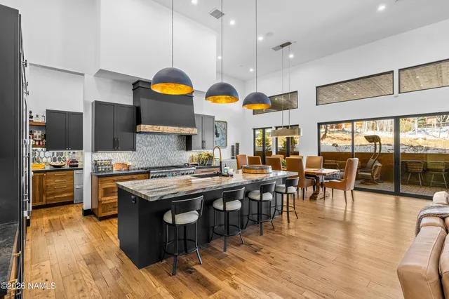 a kitchen with stainless steel appliances granite countertop a stove top oven a dining table and chairs with wooden floor