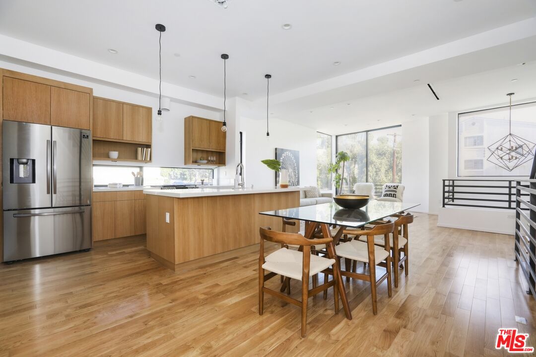 1411 West Roca Lane Los Angeles, CA 90041 - Photo 5 of 21 a kitchen with stainless steel appliances a dining table chairs a sink and white cabinets