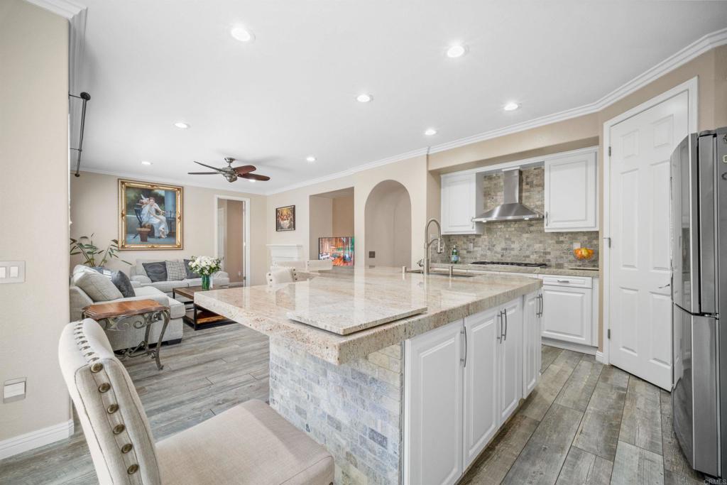2781 Rambling Vista Road Chula Vista, CA 91915 - Photo 12 of 50 a large kitchen with kitchen island a refrigerator a stove a sink dishwasher and white cabinets with wooden floor