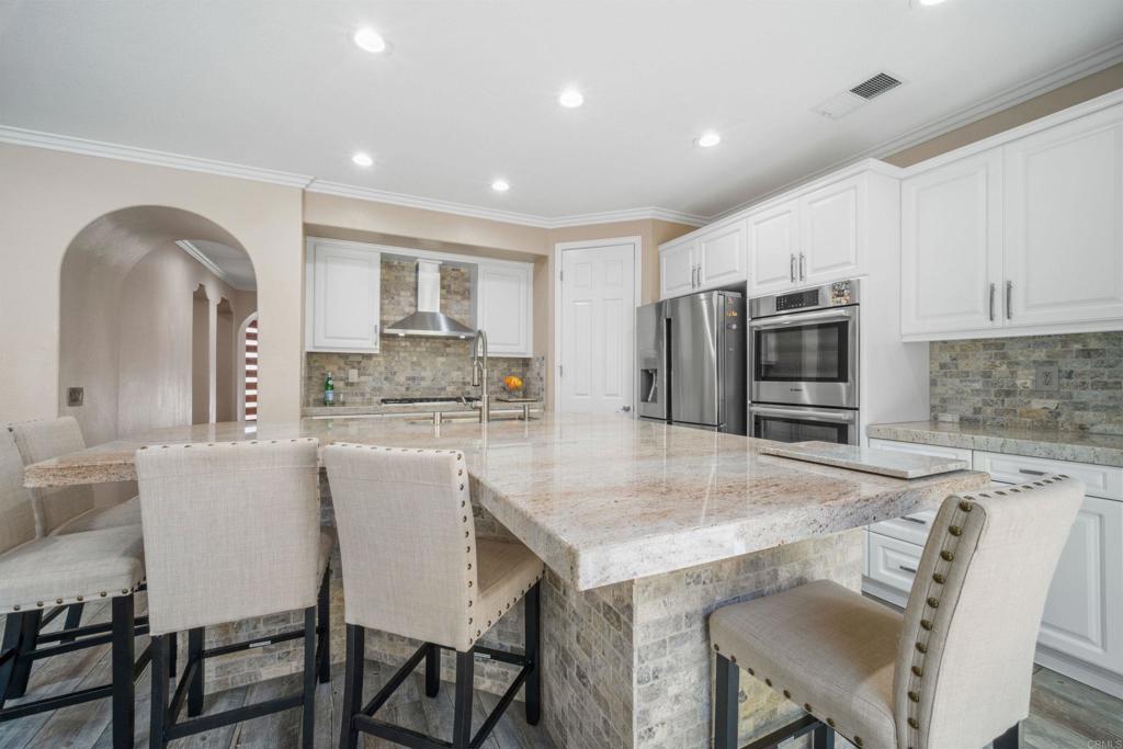 2781 Rambling Vista Road Chula Vista, CA 91915 - Photo 13 of 50 a kitchen with granite countertop a table chairs microwave and cabinets