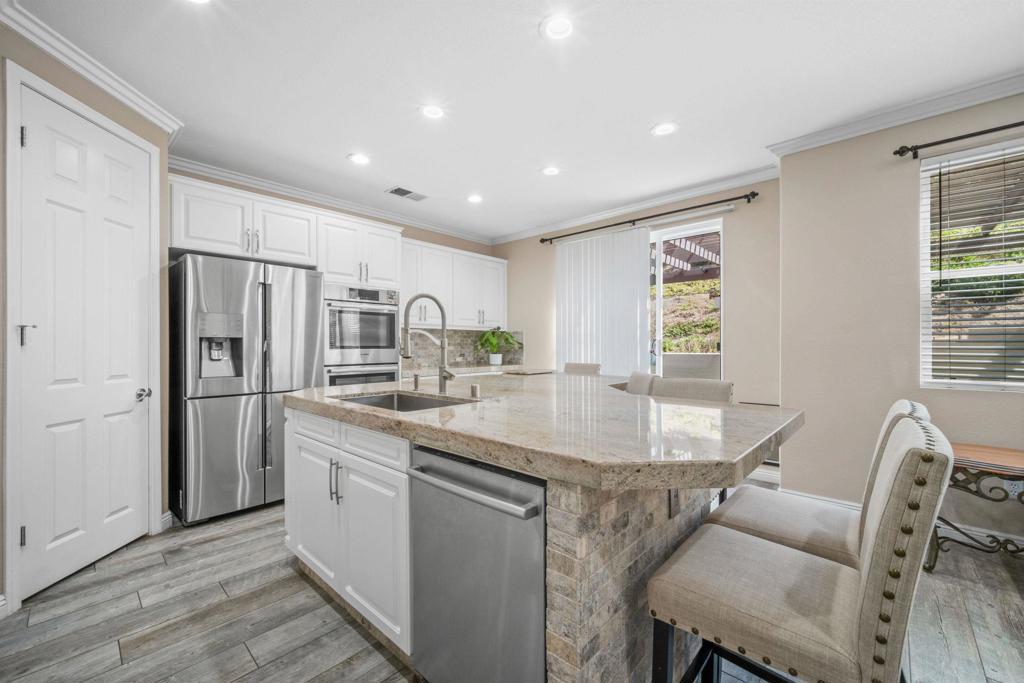 2781 Rambling Vista Road Chula Vista, CA 91915 - Photo 10 of 50 a kitchen with stainless steel appliances granite countertop a dining table chairs and refrigerator