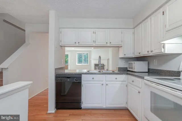 a kitchen with granite countertop white cabinets and white appliances