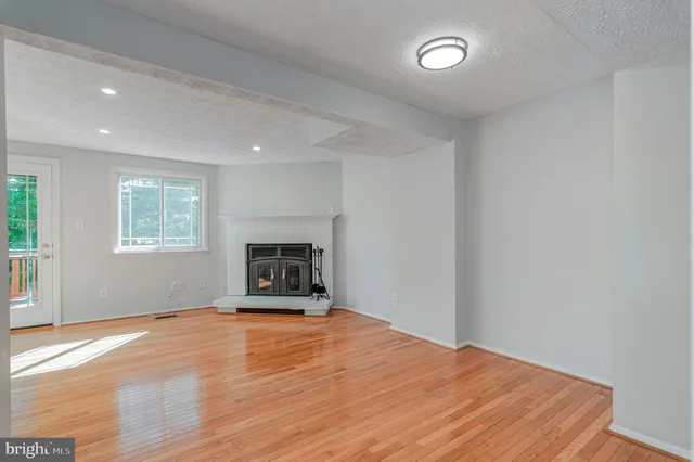 a big room with wooden floor and a fireplace