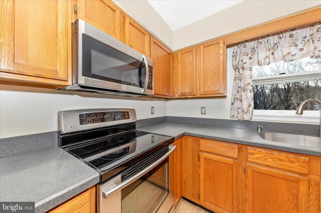 a kitchen with granite countertop cabinets stainless steel appliances and a window