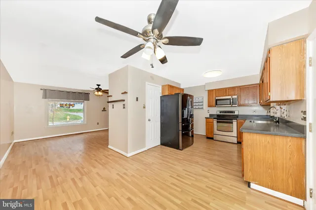 a kitchen with stainless steel appliances granite countertop a refrigerator a sink dishwasher a stove top oven a kitchen island and cabinets