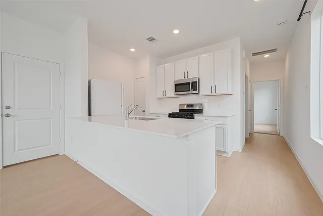 a kitchen with white cabinets and stainless steel appliances