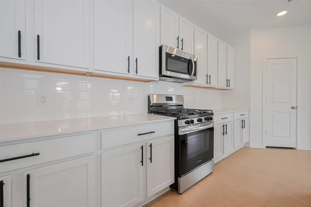 a kitchen with white cabinets and stainless steel appliances