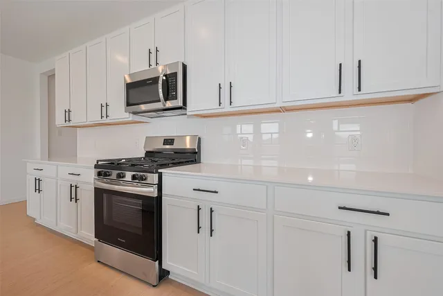 a kitchen with white cabinets and stainless steel appliances