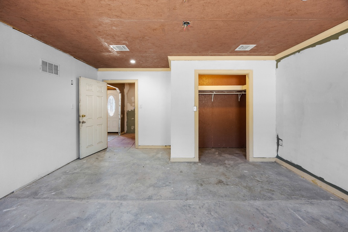 147 Community Center Road Rosanky, TX 78953 - Photo 27 of 33 Unfurnished bedroom featuring unfinished concrete flooring, a spacious closet, and crown molding