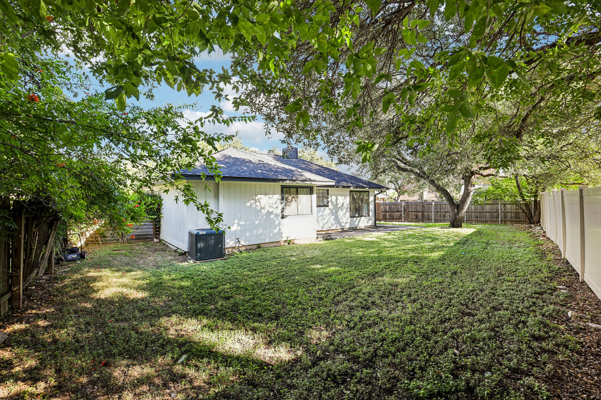 16725 Whitebrush Loop Austin, TX 78717 - Photo 24 of 32 Mature trees shade a grassy lawn bordering the rear exterior of the home.