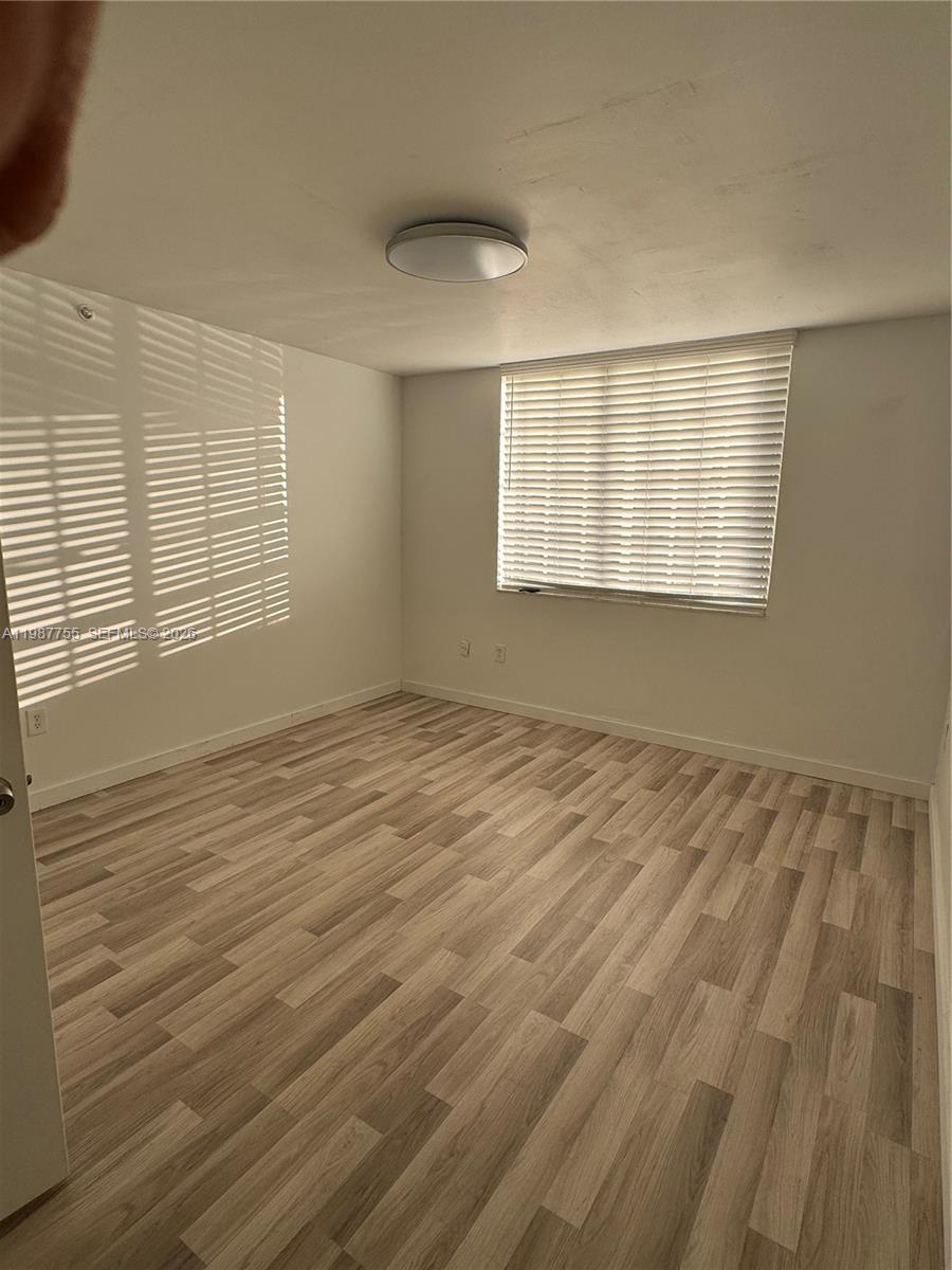 2071 Renaissance Boulevard, Unit 104 Miramar, FL 33025 - Photo 10 of 17 a view of an empty room with wooden floor and a window