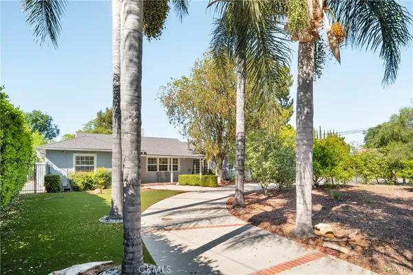 a view of a house with a yard and palm trees