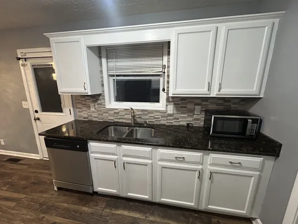 a kitchen with white cabinets and black appliances