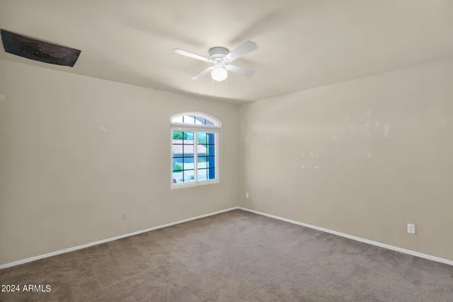 an empty room with a window and a fan