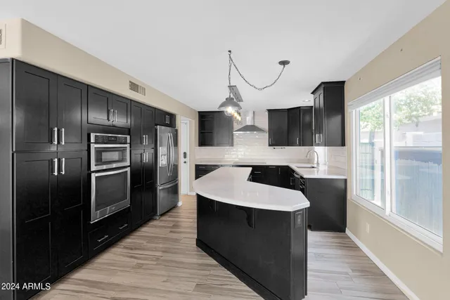 a very nice looking kitchen with a large window stainless steel appliances and cabinets