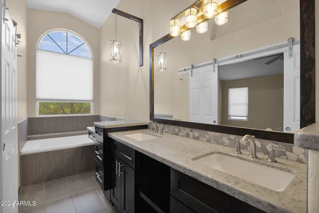 a bathroom with a granite countertop sink a large mirror and a bathtub