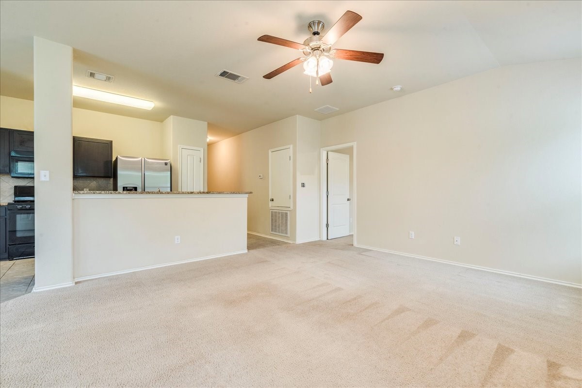 1061 Violet Lane Kyle, TX 78640 - Photo 2 of 34 Spacious living area view showing carpeted floors, ceiling fan
