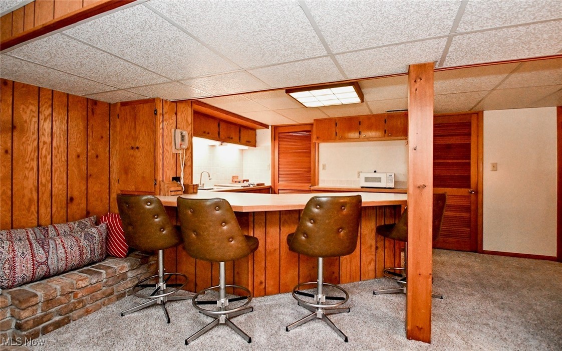 5653 Dailey Road New Franklin, OH 44319 - Photo 12 of 24 Bar featuring sink, a drop ceiling, light carpet, and wood walls